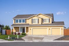 a large yellow house with two garages on the front and one attached to the side