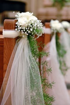 white flowers and greenery are tied to pews