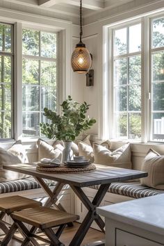 a living room filled with furniture and windows next to a wooden table topped with a potted plant