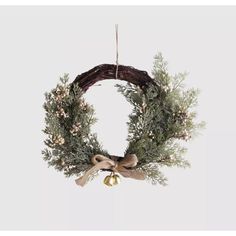 a wreath hanging from the ceiling with a bow and bells on it's side