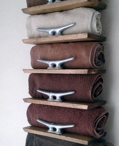 a wall mounted towel rack with five towels on it's sides and three pairs of scissors in the middle