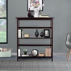 a shelf with vases and books on it in a room next to a chair