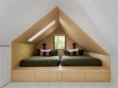 two beds sitting in the middle of a room under a slanted roof