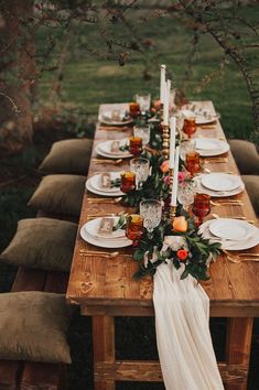 a long wooden table topped with plates and candles