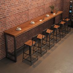 a row of bar stools next to a brick wall with plates and cups on them