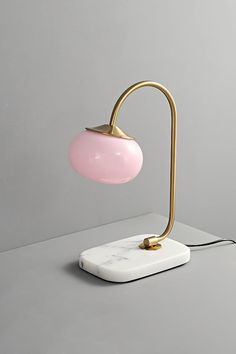 a pink lamp sitting on top of a table next to a white square plate with a black cord