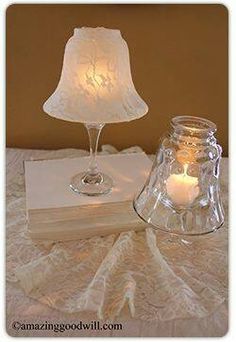 a glass lamp sitting on top of a table next to a book with a candle in it