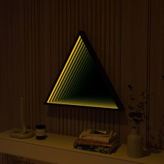 a triangle shaped lamp sitting on top of a table next to a book and vase