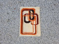 an orange and black rug on the ground next to a gray wall with a white border