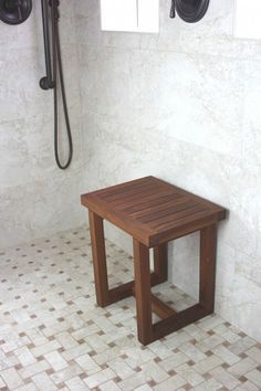 a wooden table sitting in the middle of a tiled floor next to a shower head