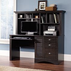 a computer desk with a monitor and keyboard on it in front of a blue wall