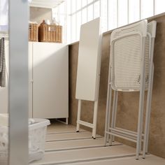 two white chairs sitting next to each other in a room with beige walls and flooring