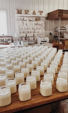 rows of jars are lined up on a table in a kitchen with other items behind them