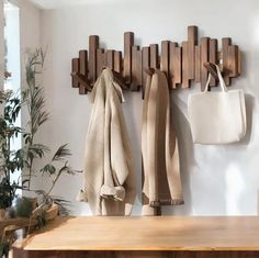 a coat rack with two coats hanging from it's sides next to a wooden bench