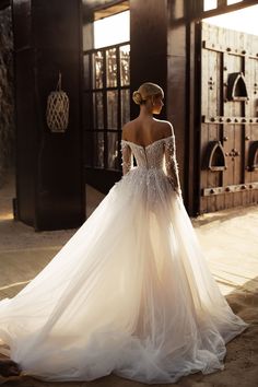 a woman in a white wedding dress standing on the ground with her back to the camera