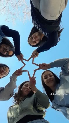 four girls standing in a circle holding their hands together and making a star with their fingers