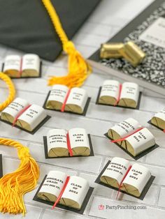 some books with tassels on top of them sitting on a table next to a graduation cap