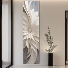 a large white flower in a vase next to a wall