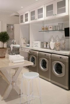 a washer and dryer sitting in a kitchen next to a table with two stools