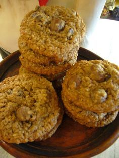 cookies stacked on top of each other on a wooden plate next to a glass of milk