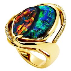 The gem at the centre of the "Contrarian" opal ring is an exquisitely unusual black opal (10.97ct) from Lightning Ridge in Australia. It showcases a rare natural marriage of two colour palates in one gemstone. Warm play of colours versus cold play of colours. A truly fascinating affair. With so much to show, this gem requires a simple yet defined setting. A sparkle of diamonds on the side adds a finishing touch. The gemstone at the centre of this opal ring is an Australian black opal from Lightn Cold Play, Black Opal Jewelry, Opal Art, Boulder Opal Ring, Australian Black Opal, Black Opal Ring, Genie Bottle, White Opal Ring, Vintage Cocktail Ring