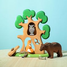 an owl, bear, and other toy animals in front of a wooden tree house