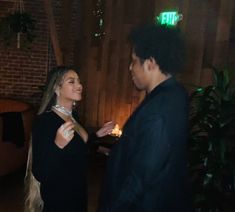 a man and woman standing next to each other in front of a table with candles