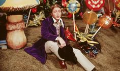 the man is sitting on the ground in front of many colorful balloons and mushrooms,