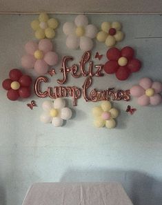 a table and chairs in a room with balloons on the wall above it that says feliz cumplanos