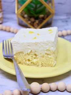 a yellow plate topped with a piece of cake next to a fork and beaded necklace