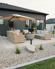 an outdoor patio with chairs and umbrellas on the grass near a house in the background