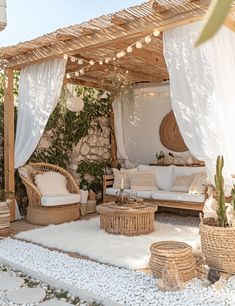 an outdoor living area with wicker furniture and white rugs on the floor, surrounded by greenery