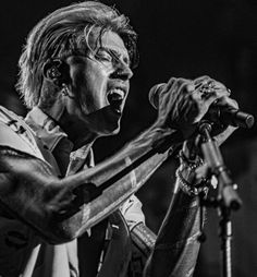 a black and white photo of a man singing into a microphone