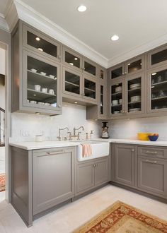 a kitchen with gray cabinets and white counter tops