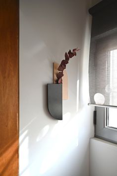 a sculpture is mounted on the wall next to a window in a room with white walls