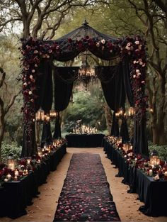 an outdoor wedding setup with candles and flowers on the aisle, surrounded by lush greenery