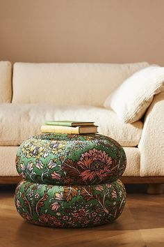 a living room with a couch, ottoman and books on the floor in front of it