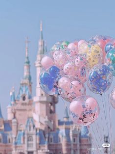 many balloons floating in the air near a castle