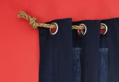 blue curtains with rope hanging from them against a red wall and an orange wall in the background