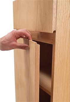 a hand is opening the door to a wooden cabinet