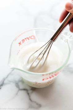 someone is whisking yogurt in a glass bowl