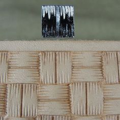 a small piece of wood sitting on top of a woven material table cloth with trees in the background