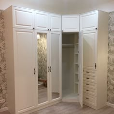 an empty closet with mirrored doors and drawers in the corner, next to a wallpapered wall