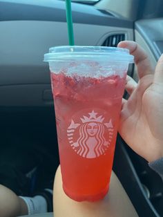 a person holding up a cup with a straw in it's hand while sitting in a car