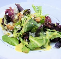 a salad with lettuce and other vegetables on a white plate topped with dressing