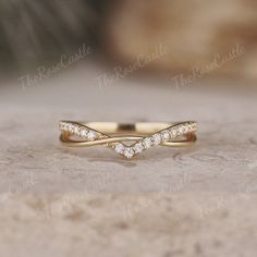 a yellow gold wedding band with three small diamonds in the middle, on top of a stone surface