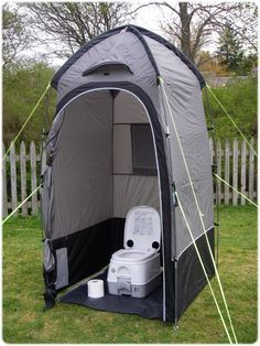 a portable toilet in the back yard of a house with an awning over it