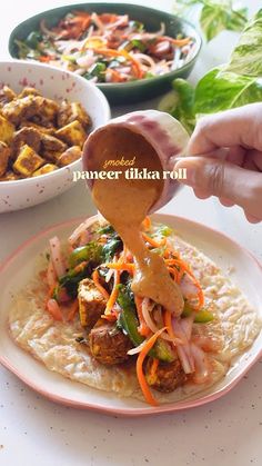 a person pouring sauce on top of a tortilla topped with meat and veggies