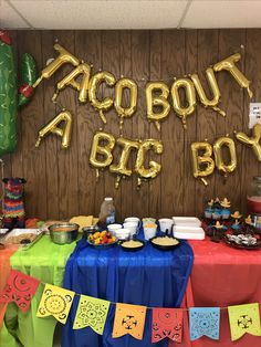 a table topped with lots of food next to a sign that says taco bout a big boy