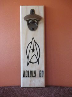 a wooden sign with a star trek emblem on it's side hanging from a wall